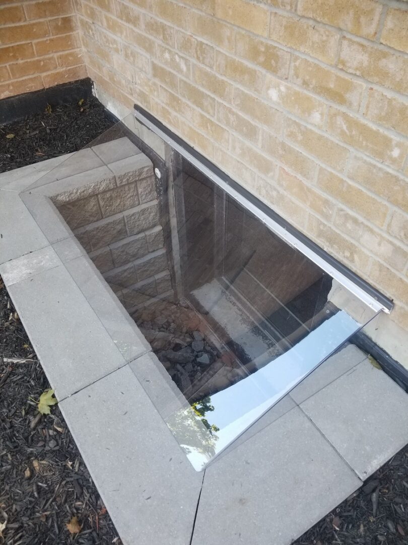 Custom clear cover over a basement window well beside a Toronto home