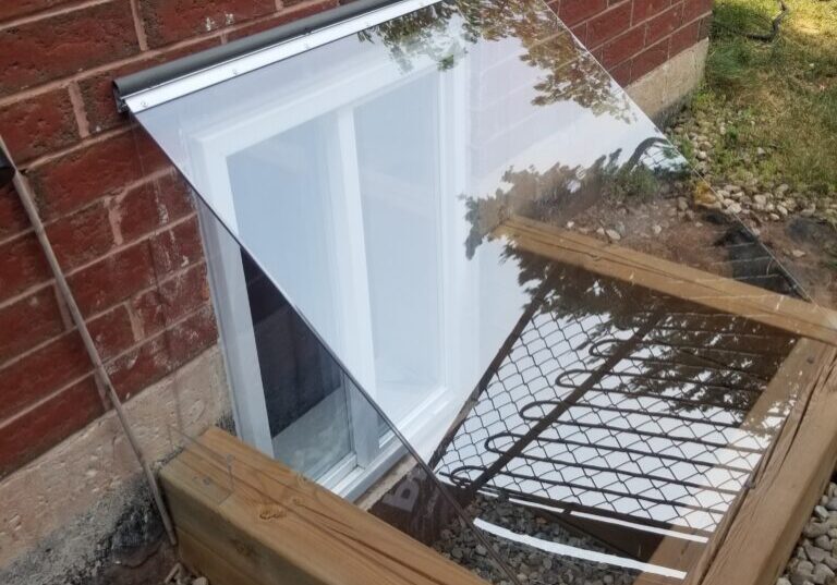 Acrylic window well cover mounted on brick wall