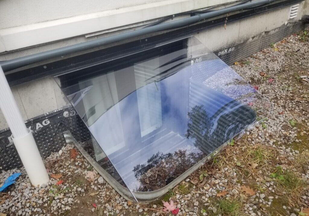 Clear acrylic window well cover reflecting trees