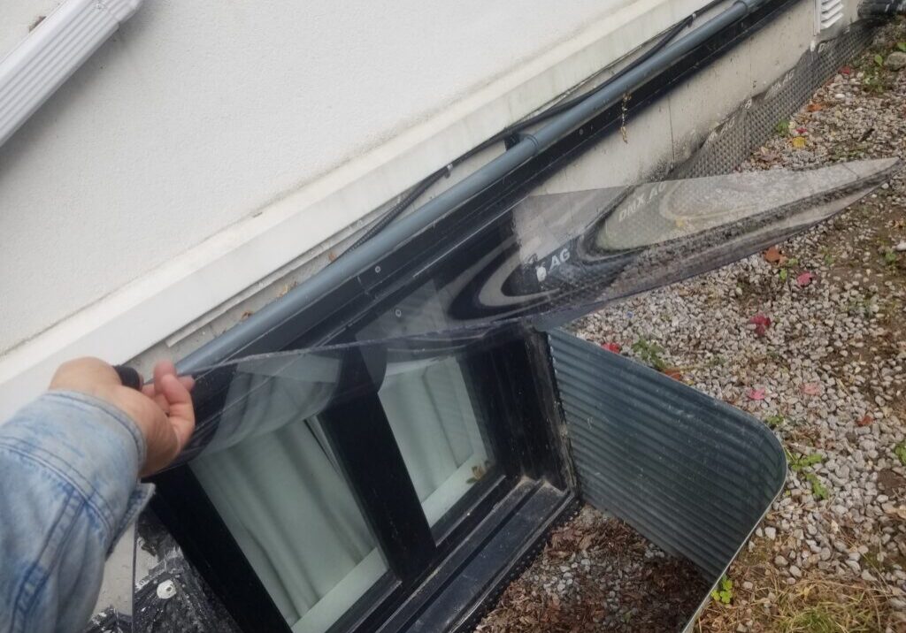 Person lifting clear window well cover